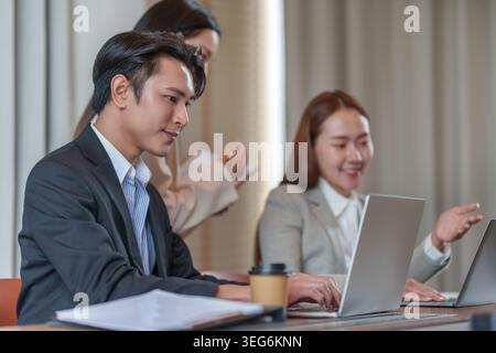 Asiatisches Business-Team, das in modernen Büros an Notebooks arbeitet Stockfoto