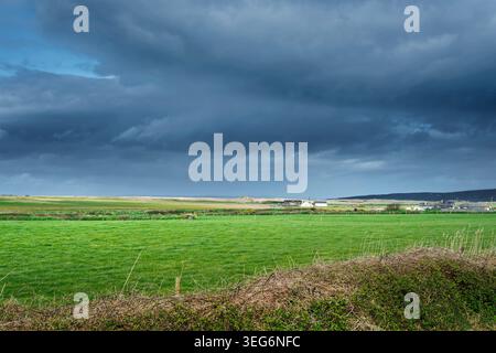 Atmosphärischer Blick auf die Landschaft von Kerry mit sonnendurchfluteten Feldern und bedrohlichen Sturmwolken am Horizont. Stockfoto