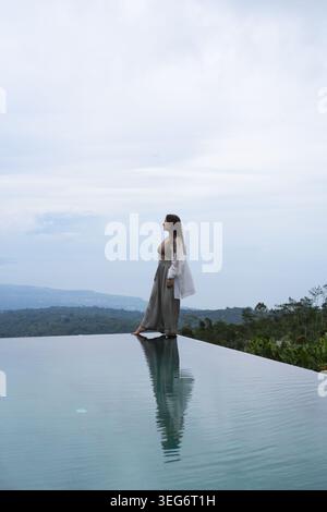 Elegante Frau in weißem Leinen mit Blick auf die Berge, Munduk, Bali Stockfoto