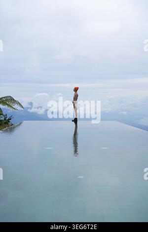 Eine junge Frau, die in den Himmel am Infinity Pool schaut, Munduk, Bali Stockfoto