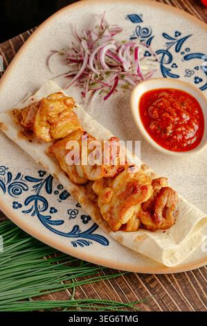 Gegrilltes Hühnchen auf Fladenbrot mit roten Zwiebeln und Sauce Stockfoto