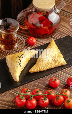 Herzhaftes gebackenes Gebäck mit frischen Kirschtomaten und Tee Stockfoto
