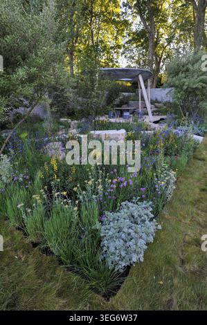 Eröffnungstag der Royal Horticultural Society Chelsea Flower Show 2023 - einer der Ausstellungsgärten: Das Eden Project: Bring Me Sunshine Garden. Dieser Garten ist von der Landschaft und Gemeinschaft der Morecambe Bay inspiriert und zelebriert Regeneration, Hoffnung und die Kraft junger Erwachsener, eine bessere Zukunft zu schaffen. Ein solarbetriebener Unterstand/Klassenzimmer mit geschwungenem Dach beherbergt Workshops, die Handwerkskunst, Gartenbau und digitales Lernen auf einer von Muscheln inspirierten Terrasse in einem reflektierenden Regenwasser-Recycling-Pool kombinieren. Eingerahmt von kalksteinhaltigen Materialien und salztoleranter Küstenwiesen-Pflanzung in Pin Stockfoto