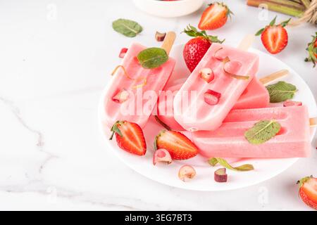 Erdbeer-Rhabarber-Eis-Eis-Eis-Eis. Gefrorenes Fruchtsorbet, Joghurt-Eis auf Sticks, mit pürierten Erdbeeren und Rhabarber und Saft, mit Zutaten o Stockfoto