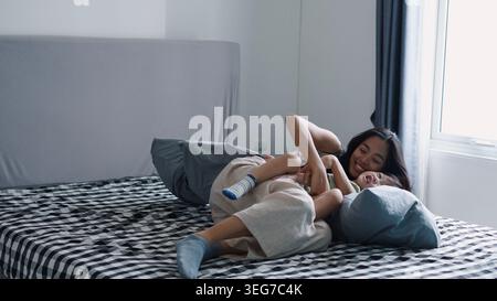 Mutter und Kind genießen das Kitzeln und Lachen während des spielerischen Moments zu Hause Stockfoto
