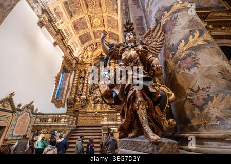 Barocke Kirche in Portugal mit einer vergoldeten Holzengelstatue neben einem kunstvollen Altar, reich bemalter Decke und verzierten Säulen, mit Stockfoto