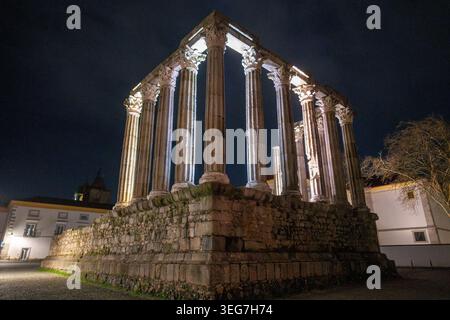 Nächtlicher Blick auf die beleuchteten römischen Tempelruinen (Tempel der Diana) auf einer erhöhten Steinplattform in Evora, Portugal. Dramatische Beleuchtung hebt Klassiker hervor Stockfoto