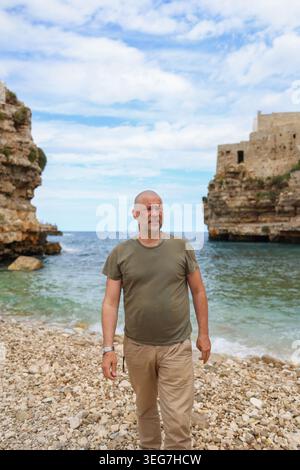 Touristen posieren am Meer in einem wunderschönen Küstendorf mit dramatischen Klippen, türkisfarbenem Wasser und authentischer Reisetmosphäre. Stockfoto