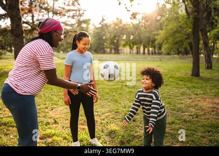 Multiethnische Familie spielt Fußball im Park Stockfoto