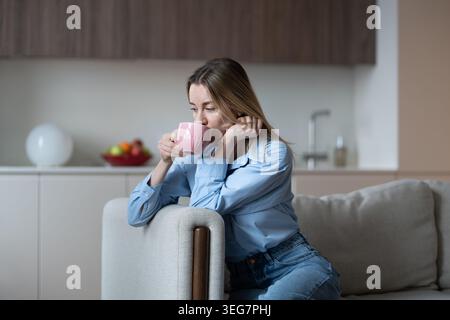 Nachdenkliche Frau mittleren Alters trinkt langsam Kaffee und fühlt sich einsam, denkt an Beziehung Stockfoto