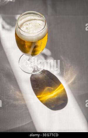 Nahaufnahme eines erfrischenden Glases Bier vom Fass, das auf einem Holztisch auf der Terrasse eines Cafés im Freien in Italien serviert wird. Erfasst während der goldenen Stunde W Stockfoto