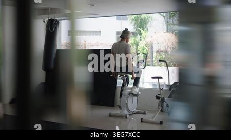Mann, der auf dem Heimtrainer im Fitnessraum trainiert, fokussiert auf Fitness Stockfoto