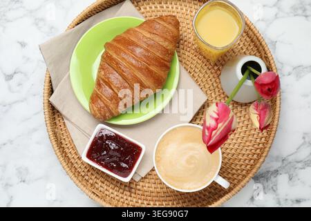 Tablett mit leckerem Frühstück und Tulpenblumen auf weißem Marmortisch, Blick von oben Stockfoto