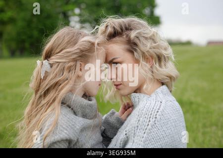 Mutter und Tochter teilen einen zärtlichen Moment, blicken sich gegenseitig in die Augen und verkörpern Liebe und Verbundenheit in einer ruhigen Umgebung im Freien. Stockfoto