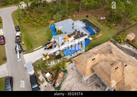 Asphaltschindeln werden auf dem neuen Hausdach aufgebracht. Dachdecker sichern Schindeln. Wohnbaustelle in Florida. Stockfoto