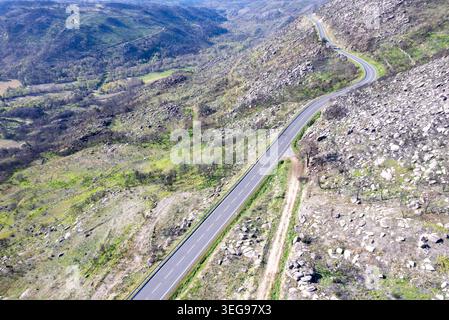 Eine kurvige Straße schlängelt sich durch ein hügeliges Gebiet und erholt sich von einem Waldbrand Stockfoto