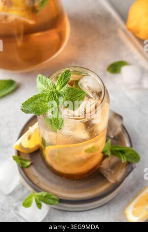 Geeister Zitronentee mit Minze im Glas auf grauem Hintergrund. Konzept für kaltes Getränk im Sommer Stockfoto