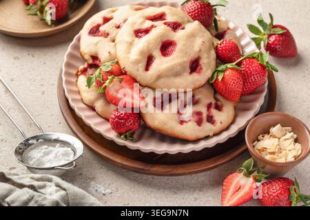Shortbread-Kekse mit Erdbeeren auf einem Teller, beigefarbener strukturierter Hintergrund. Im Sommer hausgemachtes Gebäck Stockfoto