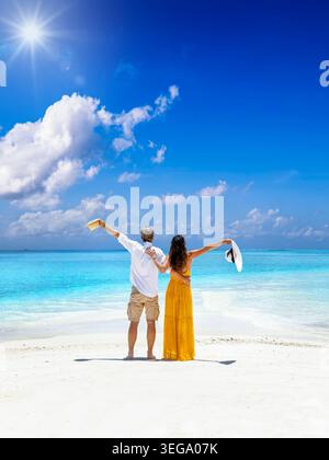 Ein glückliches Touristenpaar steht an einem tropischen Strand im Indischen Ozean und genießt den Blick über das türkisfarbene Meer, die Malediven Inseln Stockfoto