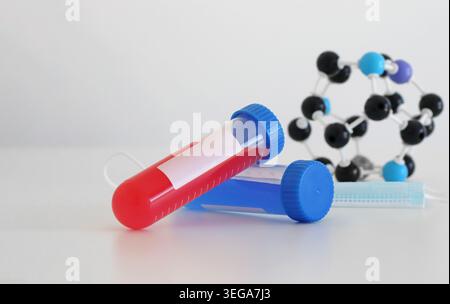 Medizinisches Reagenzglas mit molekularem Modell und Laborelementen für die Virusdiagnostik und Gesundheitsforschung. Wissenschaftliches Konzept für Infektionskrankheiten Stockfoto
