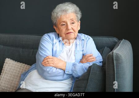 Traurige Seniorin, die zu Hause auf dem Sofa sitzt Stockfoto