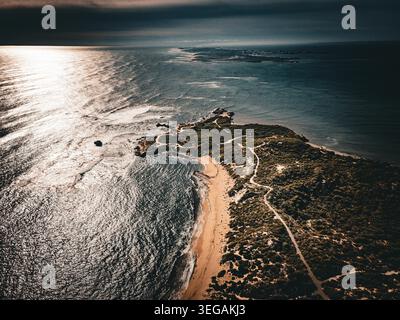 Dieses atemberaubende Luftbild fängt eine ruhige Küstenlandschaft mit einem gewundenen Sandstrand ein, der von üppigem Grün und dem schimmernden Blau umgeben ist Stockfoto