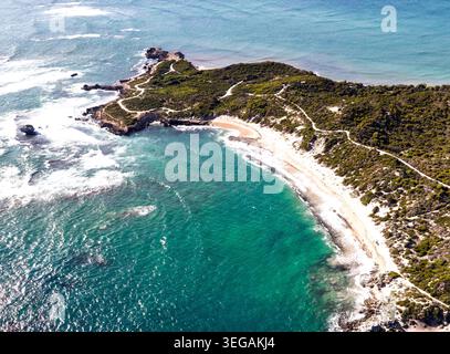 Dieser atemberaubende Blick aus der Luft fängt eine atemberaubende Küstenlandschaft mit einer gewundenen Küste, üppigem Grün und kristallklarem türkisfarbenem Wasser ein. Stockfoto