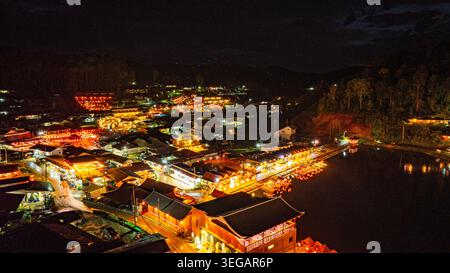 In der Abenddämmerung säumten die Lichter des Dorfes den See in chinesischen Strukturen mit farbenfrohen Lichtern. Ban Rak Thai ist Stockfoto