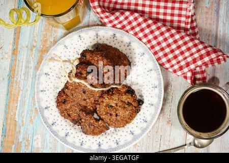 Nahaufnahme von gestapelten Haferflocken mit rustikalem Garn auf Keramikplatte mit Tee auf Holztisch. Stockfoto