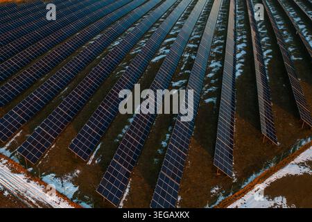 Luftaufnahme einer großen Solarpaneel-Anlage, die systematisch über einer landwirtschaftlichen Landschaft angeordnet ist. Stockfoto