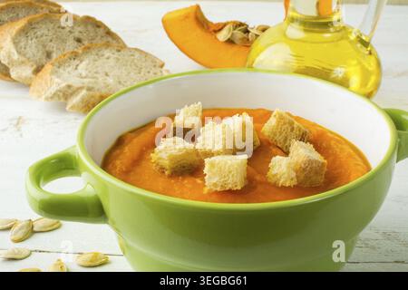 Cremige Kürbis squash Gemüsesuppe mit Croutons in einer grünen Schale und Brot auf weißem Holz Hintergrund Stockfoto
