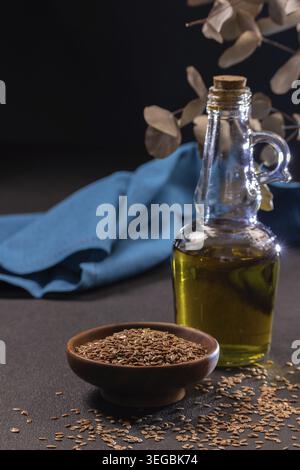 Leinsamen in einer Holzschale und Leinöl in einer Glasflasche mit natürlichen Inhaltsstoffen reich an Omega-3-Fettsäuren für eine gesunde Ernährung und Ernährung Stockfoto
