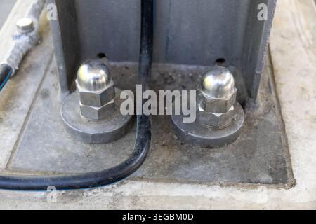 Nahaufnahme einer riesigen Edelstahl-Kappenmutter im Freien auf einer Brückensäule. Stockfoto
