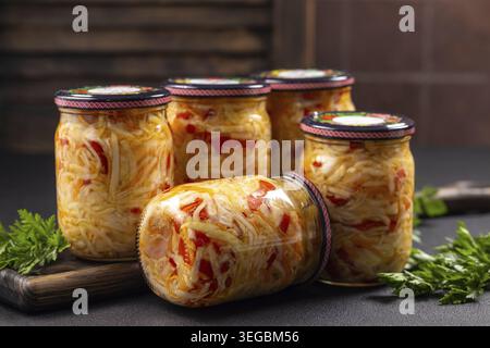 Glasgläser gefüllt mit hausgemachtem fermentiertem Kohl und rotem Pfeffersalat mit gesundem, konserviertem Gemüse, das zur Lagerung und zum Verzehr bereit ist Stockfoto
