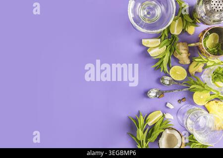 Frische Minze, Limette, Ingwer, Kokos und Ananas auf violettem Hintergrund mit Cocktail-Shaker und Gläsern für ein lebhaftes Sommergetränk Stockfoto