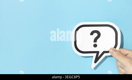 Die Hand hält ein Fragezeichen auf der Sprechblase auf blauem Hintergrund. Kopierbereich Stockfoto