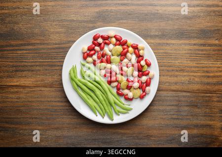 Frische grüne Bohnen und bunte Bohnen auf weißem Teller Stockfoto