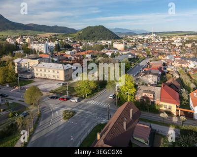 Aus der Vogelperspektive auf die Stadt Ruzomberok mit Wohnhäusern, üppigen grünen Hügeln und fernen Bergen unter einem klaren blauen Himmel Ruzomberok, Zilina Stockfoto