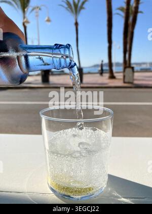 Gießen Sie ein Glas Mineralwasser über Eis und Zitrone, um im Sommer kühl zu bleiben Stockfoto