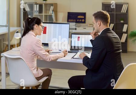 Geschäftskollegen prüfen Tabellenkalkulationen und Diagramme während der Auditsitzung im Büro Stockfoto