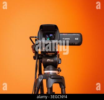 Canon Cam Recorder auf einem Stativ mit klarem, hellorangefarbenem Hintergrund Stockfoto