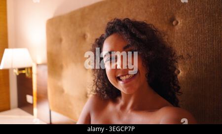 Glückliche schwarze Frau im Bett lächelnd, genießen Morgenroutine und natürliche Schönheit zu Hause Stockfoto