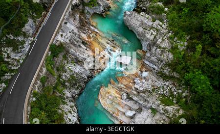 Atemberaubender Blick aus der Vogelperspektive auf den türkisfarbenen Fluss, der sich durch einen felsigen Canyon neben einer Bergstraße in Slowenien schlängelt und natürliche Schönheit und lebendige Farben bietet Stockfoto