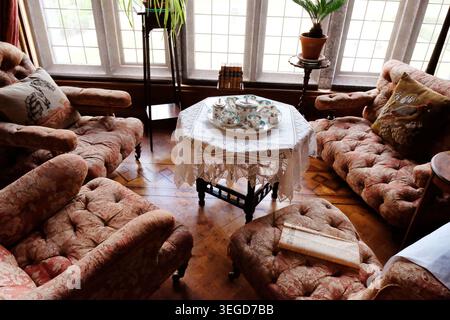 Ein elegantes Teeset aus Porzellan, das auf einer Tischdecke aus Spitze in einem historischen Landhaus-Salon angeordnet ist Stockfoto
