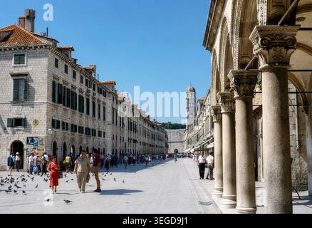 Touristen schlendern durch die Placa (Stradun) in Dubrovnik, Jugoslawien, Ende der 1950er Jahre Die Aussicht zeigt den historischen Uhrenturm und die elegante Renaissance- und gotische Architektur des Rektorenpalastes, während die Menschen die Sonne im Herzen der alten ummauerten Stadt genießen. Stockfoto