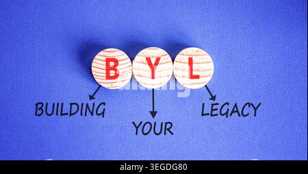 BYL baut Ihr altes Symbol auf. Concept Words BYL baut Ihr Vermächtnis auf wunderschönen Holzkreisen auf. Wunderschöner blauer Hintergrund. Business BYL Gebäude Stockfoto