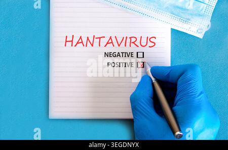 Hantavirus medizinisches Symbol. Konzeptworte Hantavirus positiv auf schöner weißer Note. Wunderschöner blauer Hintergrund. Arzthand in blauem Medizinhandschuh. Ich Stockfoto