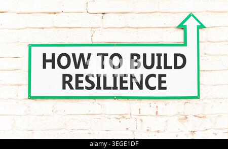 So erstellen Sie ein Resilienzsymbol. Konzeptworte wie man Widerstandsfähigkeit auf einem schönen weißen Schild schafft. Wunderschöner Backsteinmauerhintergrund. Geschäftsanweisungen Stockfoto