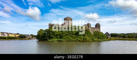 Blick auf Pembroke Castle auf einem üppig grünen Hügel mit Blick auf das ruhige Wasser unter einem blauen Himmel mit schimmernden Wolken in Pembroke, Wales, Großbritannien Stockfoto