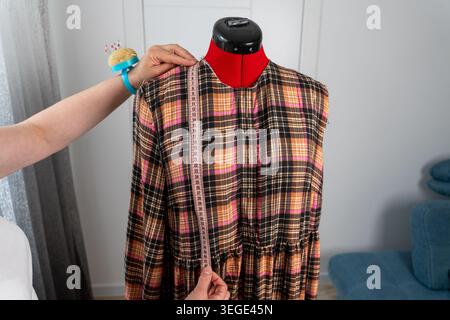 Frau, die Körpermaße an der professionellen Schneiderpuppe während der Schneiderei und des Nähprozesses im Atelier nimmt. Modedesigner arbeitet mit Measur Stockfoto